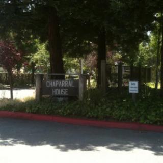 A scenic view of a park entrance with trees and signage.