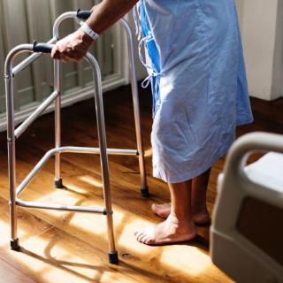 A patient using a walker in a hospital room for rehabilitation.