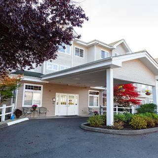 The front entrance of a building with landscaped surroundings and a covered porch.