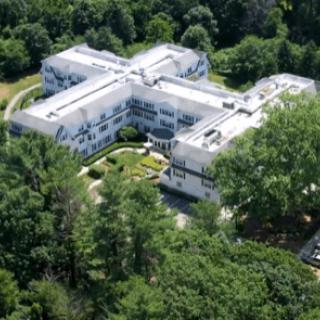 Aerial view of a large building complex surrounded by trees and greenery.