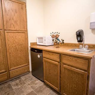 A compact kitchen area with wooden cabinets, a microwave, and a sink.