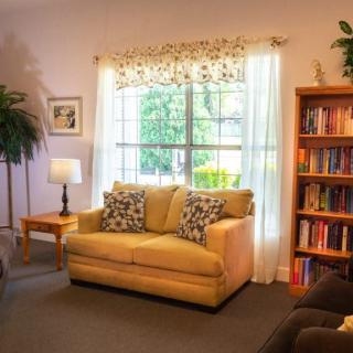 A cozy living room featuring a comfortable sofa, a well-stocked bookshelf, and a large window letting in natural light.