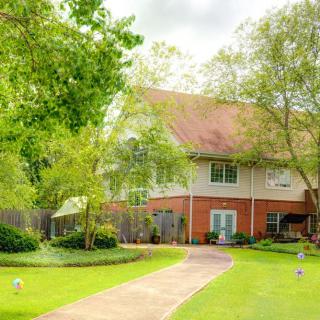 A serene house surrounded by lush greenery and a well-maintained garden.