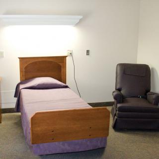 A minimalist bedroom with a single bed and a reclining chair.