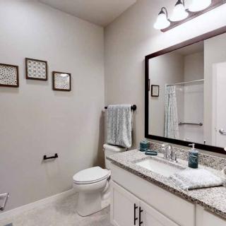 A modern bathroom with a large mirror, granite countertop, and tasteful decor.