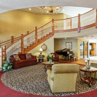 A spacious lobby featuring a grand staircase, comfortable seating, and elegant decor.