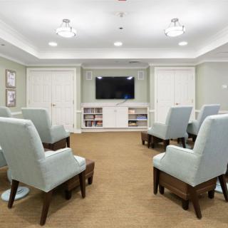 A cozy meeting room with comfortable chairs arranged around a television.