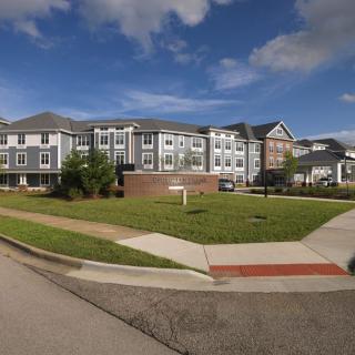A modern apartment building with a well-kept lawn under a partly cloudy sky.