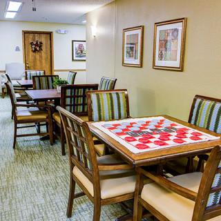 A cozy game room with tables and chairs, featuring a checkered board for games.