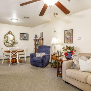 A cozy living room with a sofa, armchair, and dining area, featuring warm lighting and decorative details.