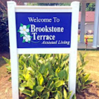 Sign for Brookstone Terrace Assisted Living surrounded by plants.
