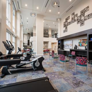 A modern gym with various exercise machines and ample natural light.