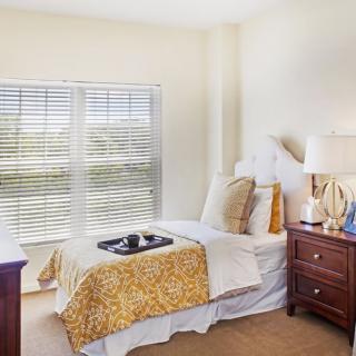 A cozy bedroom with a neatly made bed, wooden furniture, and a bright window.