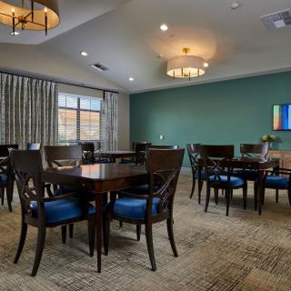 A well-lit dining room with multiple tables and chairs, featuring elegant lighting fixtures and modern decor.