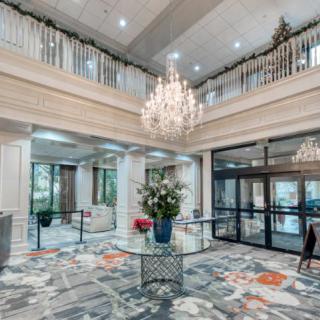 A spacious and elegantly designed lobby featuring a grand chandelier and floral centerpiece.