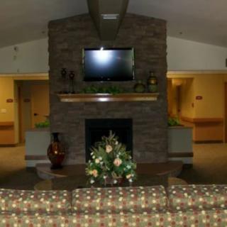 A cozy living room with a stone fireplace, mounted TV, and comfortable seating.