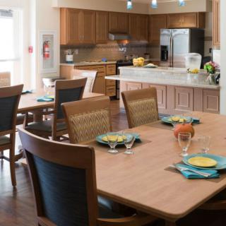 A modern kitchen and dining area with wooden furniture and a neatly set table.