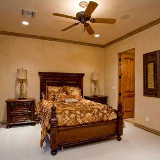 Cozy bedroom with a wooden bed frame, nightstands, and a ceiling fan.