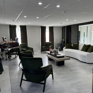 A modern and minimalist living room featuring green chairs and a white sofa, filled with natural light.