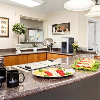 A well-organized kitchen countertop featuring sandwiches and coffee mugs, with modern decor and lighting.