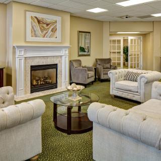 A cozy living room with elegant sofas, a fireplace, and a glass coffee table.