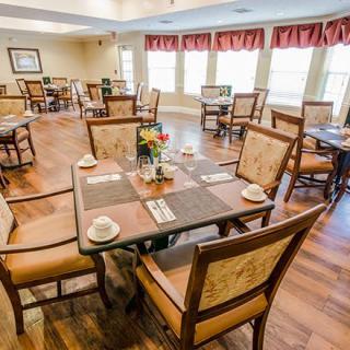 A cozy dining room with multiple set tables and wooden flooring.