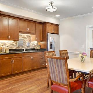 A cozy kitchen and dining area with wooden cabinets, hardwood flooring, and a modern light fixture.