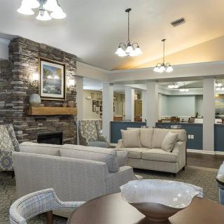 A modern living room with comfortable sofas and a fireplace, illuminated by hanging chandeliers.