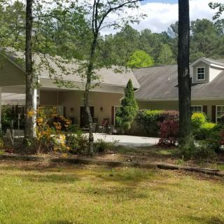 A serene residential house surrounded by trees and a well-maintained garden.