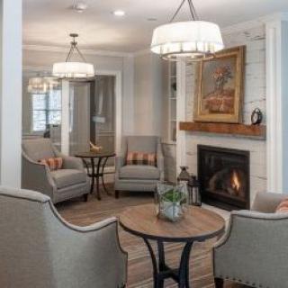 A cozy living room with armchairs, a fireplace, and elegant chandelier lighting.