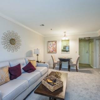 A cozy living room with a sofa, coffee table, and adjacent dining area featuring modern decor and artwork.