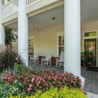 A charming porch with rocking chairs, surrounded by a vibrant garden of flowers.