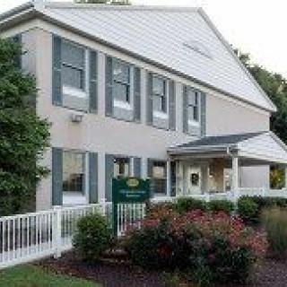 A two-story building with a landscaped front yard and a small porch.