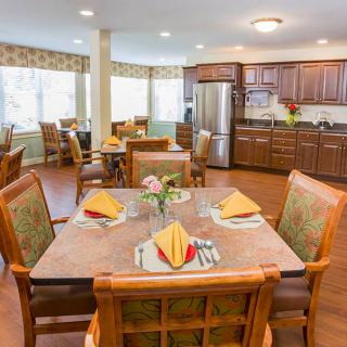 A warmly decorated dining area with set tables and a view of the kitchen.