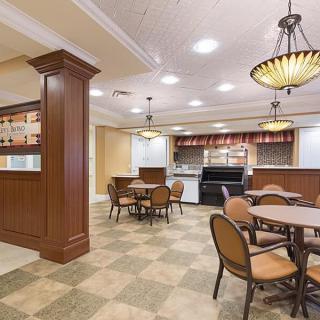 A well-lit dining area with tables and chairs adjacent to a kitchen space.