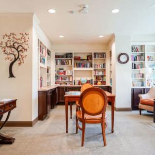 A cozy study room with bookshelves, a central table, and comfortable seating.