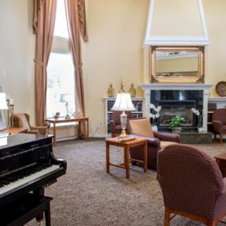 A cozy living room featuring a grand piano, comfortable seating around a fireplace, and tasteful decor.