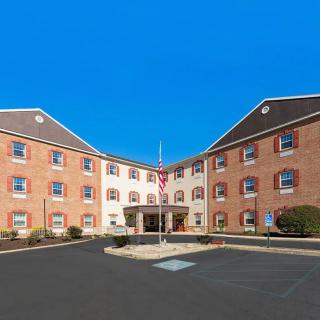 A symmetrical brick hotel building with an entrance and flagpole in front.