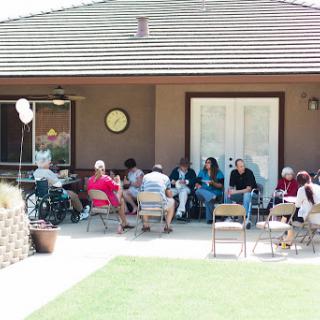 A group of people enjoying a sunny day outdoors, gathered in a communal setting.