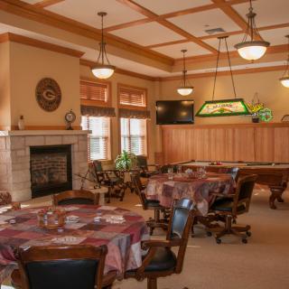 A cozy dining room with multiple tables, a fireplace, and a pool table.