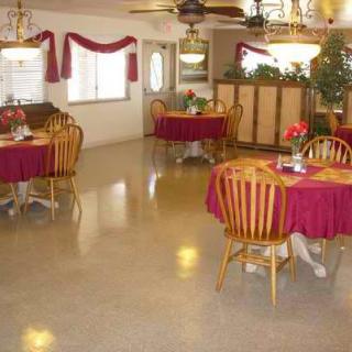A cozy dining area with wooden chairs and tables covered in red tablecloths.