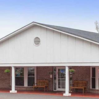 The image shows the exterior of a single-story building with a gabled roof and brick facade.