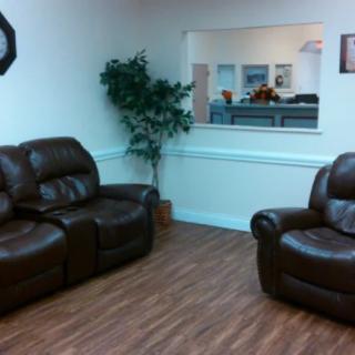 A cozy waiting room with leather seating and a view of the reception desk.