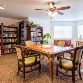 A cozy reading room with bookshelves, a wooden table, and chairs.
