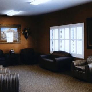 A cozy living room with sofas, a painting, and a window with blinds.