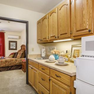 A cozy kitchen area with wooden cabinets, adjacent to a living room.