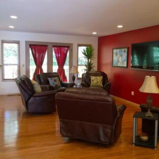 A cozy living room with leather seating, a red accent wall, and natural light.
