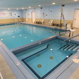 An indoor swimming pool with an attached jacuzzi and seating area.