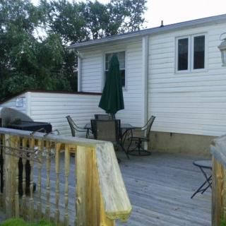 A wooden deck attached to a house with outdoor furniture, an umbrella, and a grill.
