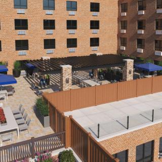 Rooftop patio with seating and umbrellas surrounded by apartment buildings.